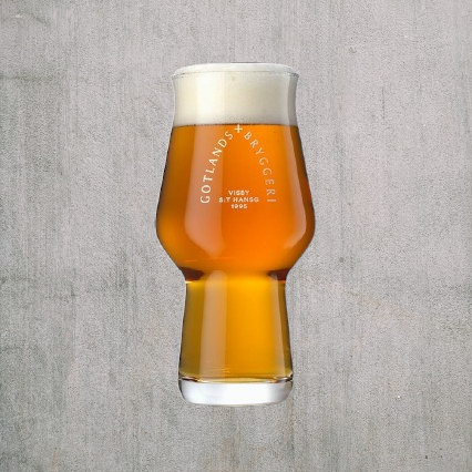 Glas med logo gotlands bryggerier med öl i skum på toppen mot grå bakgrund