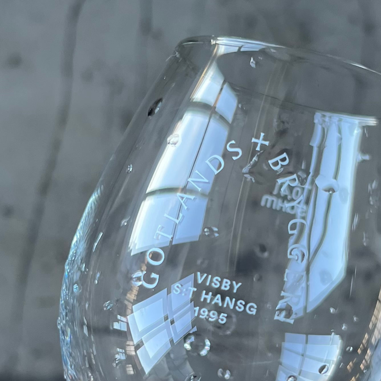 Glas fyllt med öl med skum på toppen. Blått hav i bakgrunden