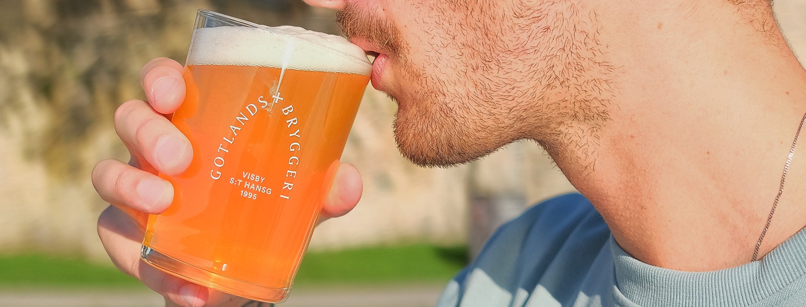 Man där man ser halva ansiktet drickandes ur ett ölglas med Gotlands bryggeri logo på