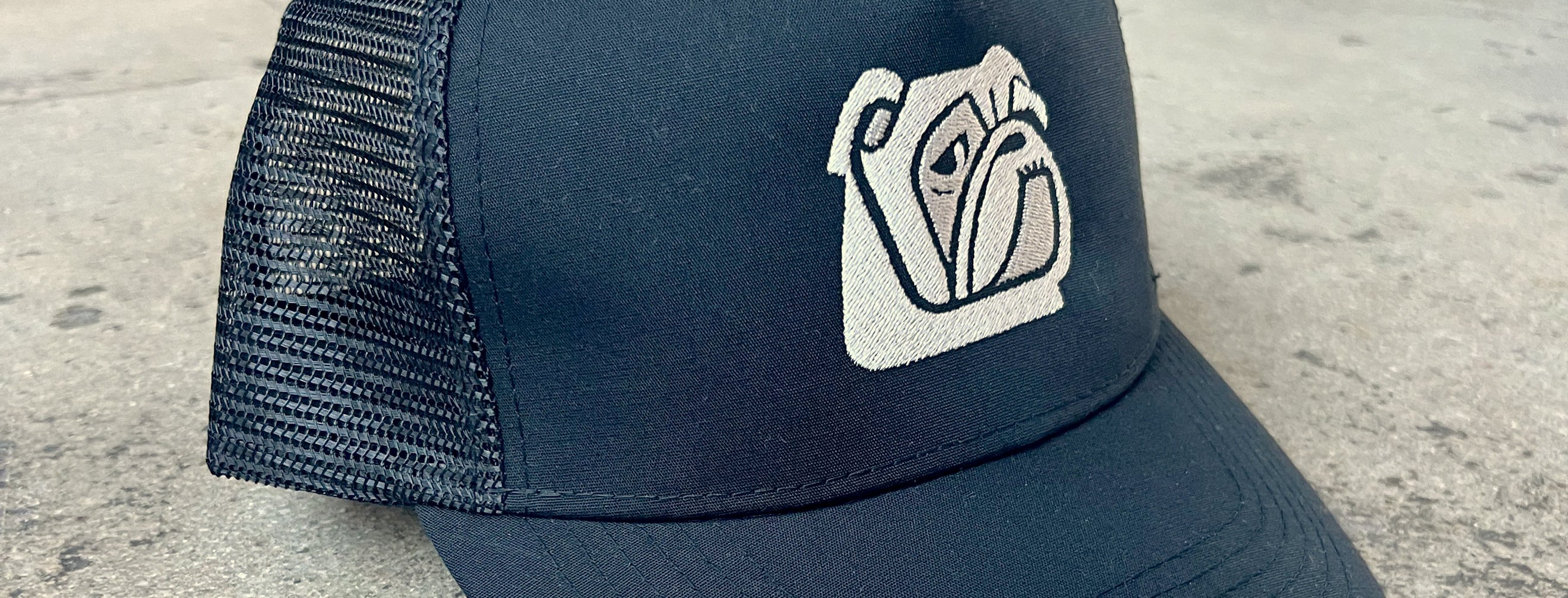 Närbild på en svart keps med logo Bulldog broderad i grått