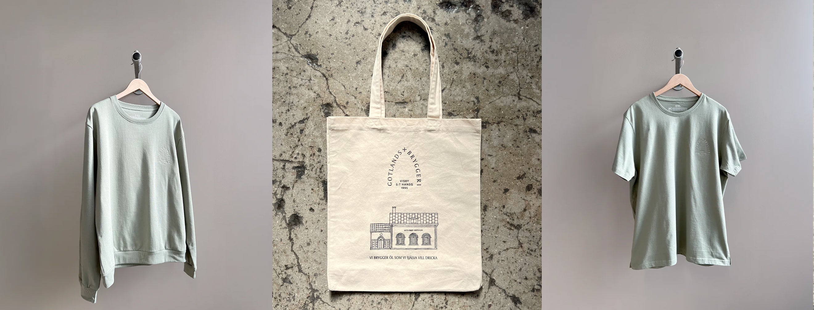 Grön sweatshirt hängande på galge mot grå bakgrund. Naturfärgad totebag mot stenbakgrund. Grön t-shirt hängande på galge mot grå bakgrund. 