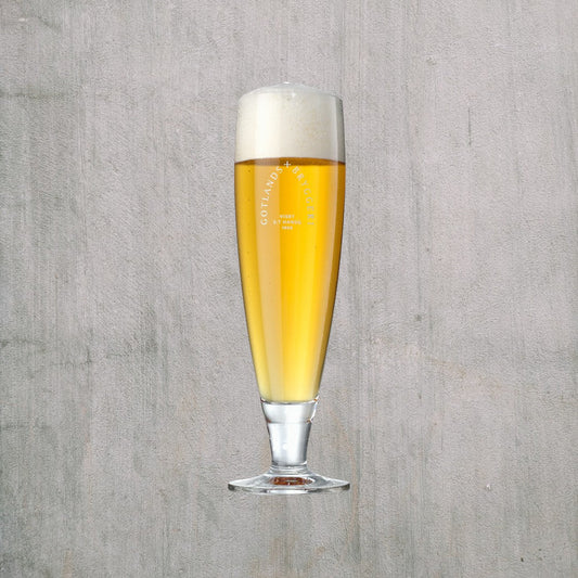 Glas med logo gotlands bryggerier med öl i skum på toppen mot grå bakgrund